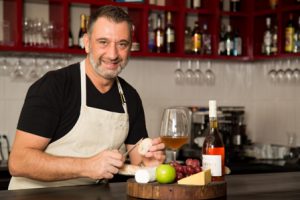 El Chef Migny detrás del comptoir de Tanino Bistro donde siempre recibe a sus clientes presentando su maridaje favorito, un Chèvre elaborado localmente por Kiaora Farms y un Comté de 14 meses importado con un vino Oremus Tokaji Aszú.